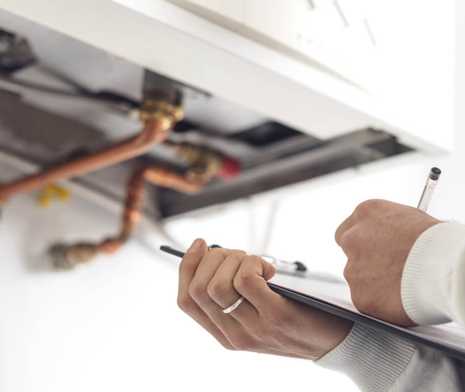 Wartung einer Heizanlage: Mann schreibt auf Klemmbrett